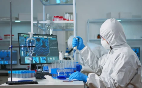 Man scientist in coverall using micropipette in modern equipped laboratory.