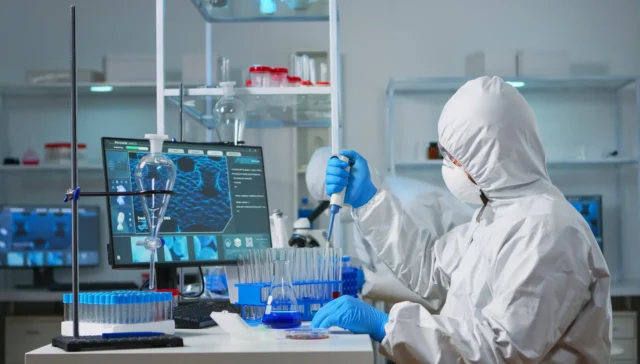 Man scientist in coverall using micropipette in modern equipped laboratory.