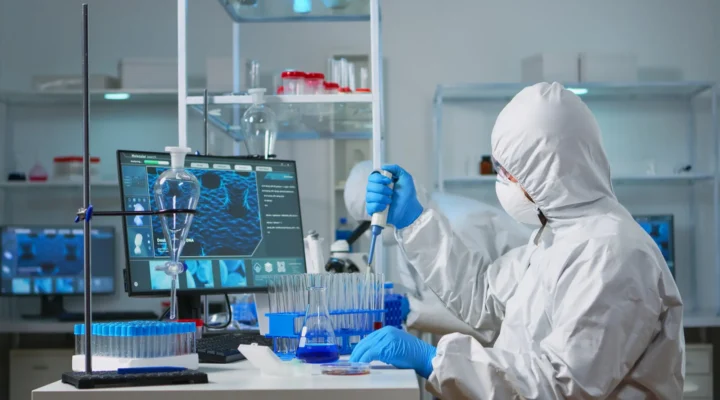 Man scientist in coverall using micropipette in modern equipped laboratory.