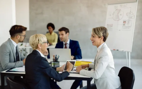 happy female colleagues talking during business meeting in the office