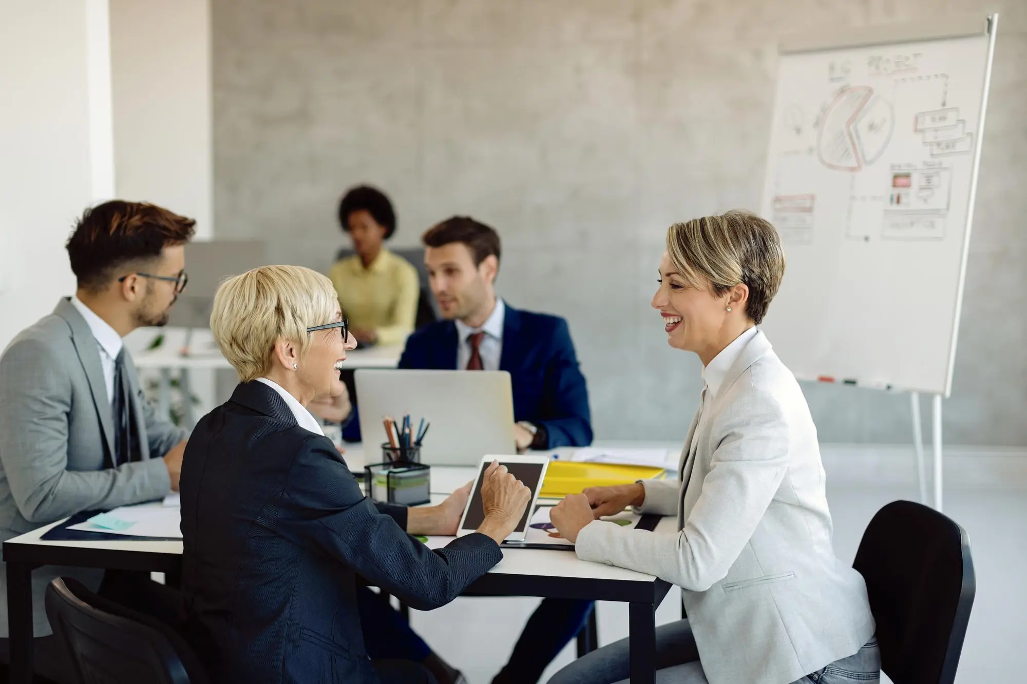 happy female colleagues talking during business meeting in the office